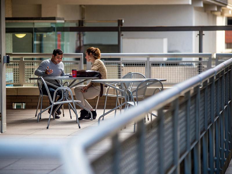 A guy talks to another student on campus. 